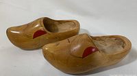 Pair of wooden clogs showing left and right shoe side views with hand painted red and black decorative details.