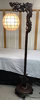 Full view of the carved wood dragon-themed floor lamp with shell globe shade