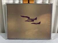 Front view of the framed photo showing three Blue Angels jets flying in formation against cloudy sky background, plastic box frame visible.