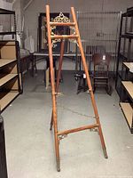 Full view of wooden display easel with decorative metal fittings and chain support