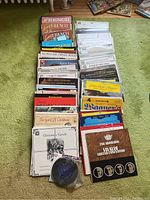 Assorted vinyl records laid out on carpet showing variety of genres including French, classical, orchestra, Christmas, and others with visible titles and cover art.