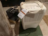 Whirlpool dehumidifier next to Biotech humidifier on floor, power cords visible.