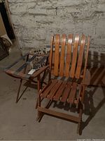 Front and side views of vintage wooden rocking chair and adjacent wooden luggage holder with fabric straps.