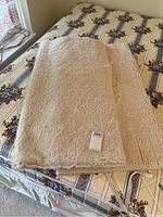 Two twin sized wool bed covers folded and placed on a bed with patterned mattress and foundation visible beneath.