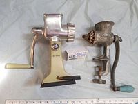 Two vintage metal food processors side by side with a ruler and box for scale.