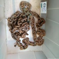 Full view of rusty heavy duty chain approximately 10 feet long inside a white container, showing chain coiled with a lot label.