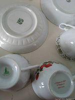 Bottom of china plates and cups showing manufacturer stamps and signatures confirming vintage signed china originals