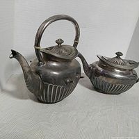 Two-piece vintage Middletown Plate Co. silverplate coffee pot and teapot set shown side by side on light patterned fabric.