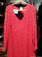 Front view of coral lace sequin dress with long sleeves hanging on hanger showing texture and color.