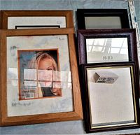 Photo of five wood picture frames with various finishes and sizes arranged on a flat surface for display.
