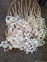 Several long strands of small white seashells arranged in a circular pattern on the floor.