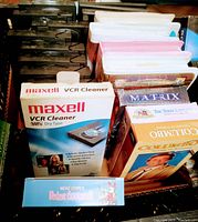 Top view of various VHS tapes showing Maxell VCR cleaner tape in original box, and visible VHS movie titles including Columbo and The Lone Ranger.