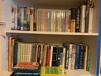 Bookshelf filled with assorted hardcover and paperback books in varied colors and sizes