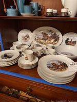 Wide view showing full set of porcelain dishes with wildlife motifs including plates, cups, saucers, large bowl, and serving platter
