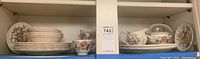 Full view shelf of Johnson Brothers Sheraton china pieces including stacked plates, bowls, cups, and covered serving dishes arranged on shelf.
