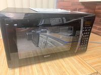 Front and side view of black Kenmore microwave oven with digital keypad on right side and transparent door with mesh.