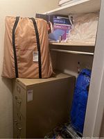 Overview showing Simply Sleeper twin mattress pad carrying bag, beige mattress pads, and brand label tags