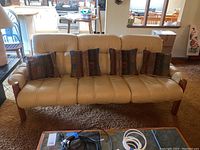 Front view of cream leather Ekornes sofa with four patterned throw pillows