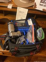 Sony DSC-F707 digital camera and accessories in black and red carrying case on wooden table.