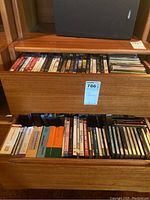 Two wooden drawers partially open showing VHS tapes, DVDs, and CDs stacked inside.