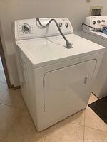 Full view of white Whirlpool electric dryer showing front door and power cord on top.