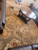 View of the area rug between leather sofas and a coffee table.