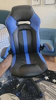 Front view of the leather gaming chair showing black and blue panels, padded armrests, and ergonomic design.