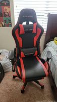 Front view of the black and red GTRACING leather gaming chair showing ergonomic shape and attached cushions