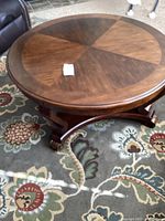 Round wooden coffee table, top view showing wood grain pattern and surface wear.