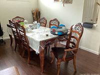 Six wooden dining chairs around a dining table with two captain chairs at heads and four regular chairs on sides.