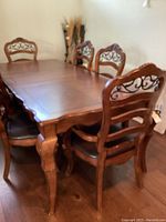 Full view of wooden dining table with six matching chairs around it, showing table top, legs, chair backs and seats.