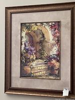 Framed painted artwork showing stone steps and archway with colorful flowers and plants in pots.