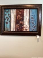 Framed mixed medium floral wall art showing vertical panels with flowers in teal, brown, beige colors.