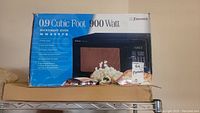 Photo of the microwave oven box, showing brand Emerson, model MW8997B, 0.9 cubic foot, 900 watts.