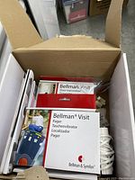 Open cardboard box showing Bellman Visit door transmitter device in red and white and Bellman Visit pager unit box.