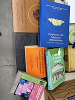 Photo showing medical pathology books focused on neoplasms and melanomas, including titles on sebaceous and follicular differentiation.