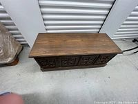 Top view of the large cedar blanket chest showing carved wood front and flat top.