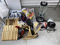 Wide view showing wooden cutting boards, multiple utensils in a woven basket, blender, and small crockpot