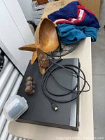 Laser disc player with HDMI cable, wooden pineapple bowl, blankets and small carved figurine on top