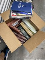 Top view of a box filled with various medical books, many on pathology and diagnostic medicine, in mixed colors and bindings.