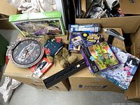 Overview of lot showing Star Trek Phaser and Tricorder toys, puzzles, racing clock, teddy bear, collectible car, display stand.