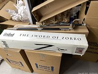 Photo of the sword and sheath in the original United Packaging box labeled 'The Sword of Zorro' with the sword partially visible lying on top of the box.
