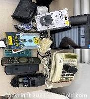 Photo showing remotes, phones for the deaf, binoculars, and other small accessories arranged on a flat surface