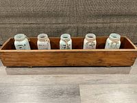 Front view of the long wooden trough with five chalk painted mason jars inside