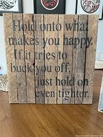 Front view of large wooden sign with motivational text printed in black on vertical wooden slats.
