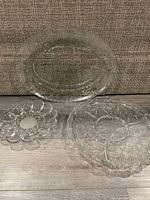 Three clear glass platters, showing the different sizes and designs including oval platter and deviled egg dish