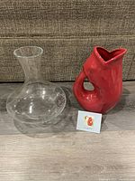 Red Gurgle Pot alongside the glass decanter with brand card in front