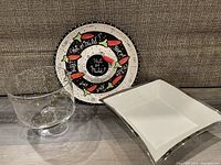 Three serving pieces shown: painted chili pepper salsa platter, white silver-trimmed square bowl, glass gold dotted bowl