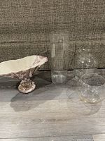 Four vases displayed on floor in front of couch: one rose with gold, three clear glass in various shapes