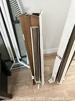 Two sets of custom window blinds standing upright with white framing and wooden slats visible.